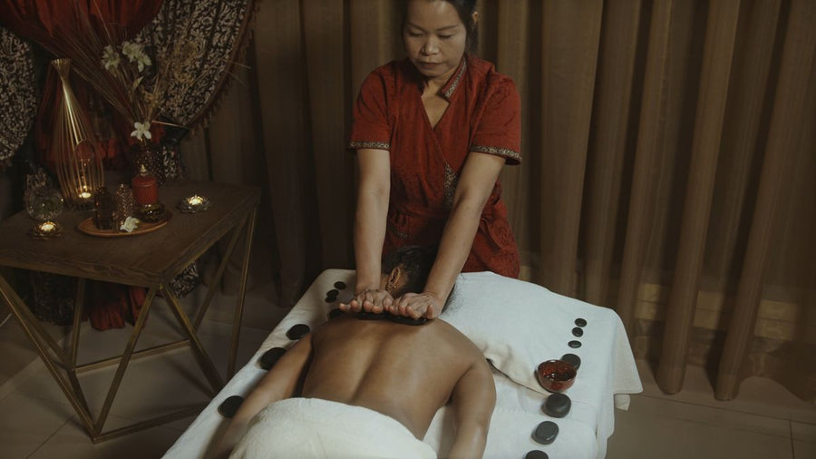 Hot-Stone-Massage mit warmen Basaltsteinen entlang der Wirbelsäule
